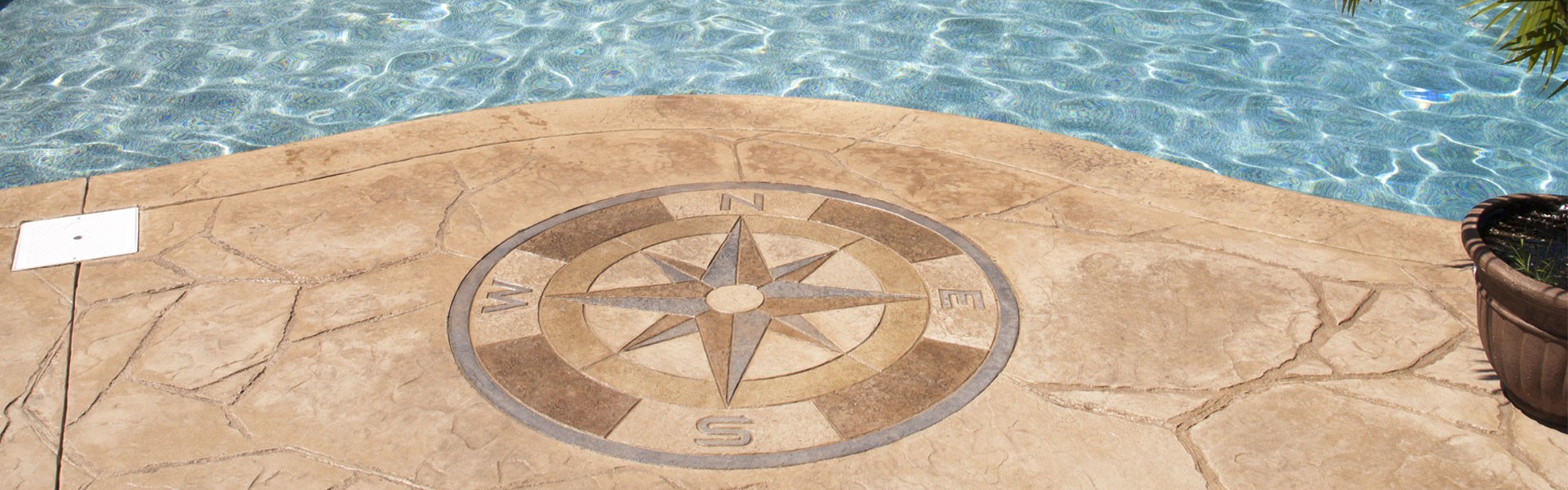 Compass made out of concrete near a pool.